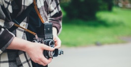 Person in plaid shirt holding a camera